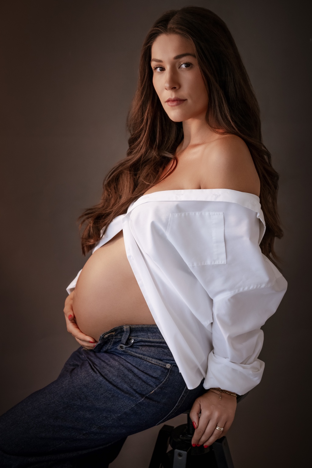 Elegantes Babybauchportrait vor dunklem Hintergrund