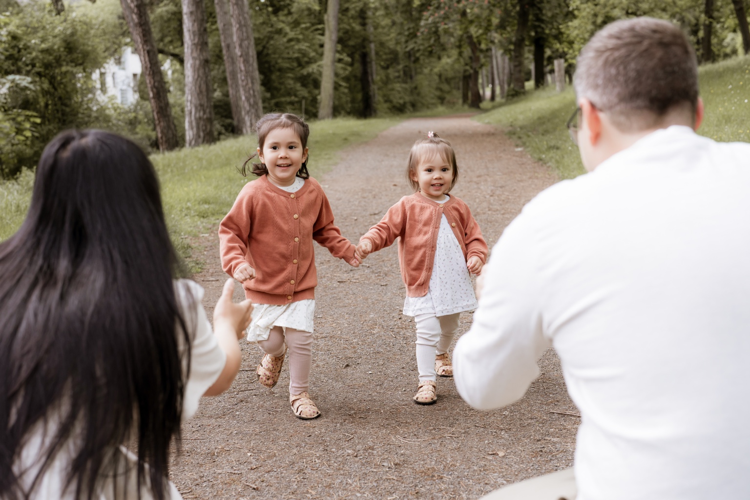Zwei Kinder laufen ihren Eltern im Grünen entgegen