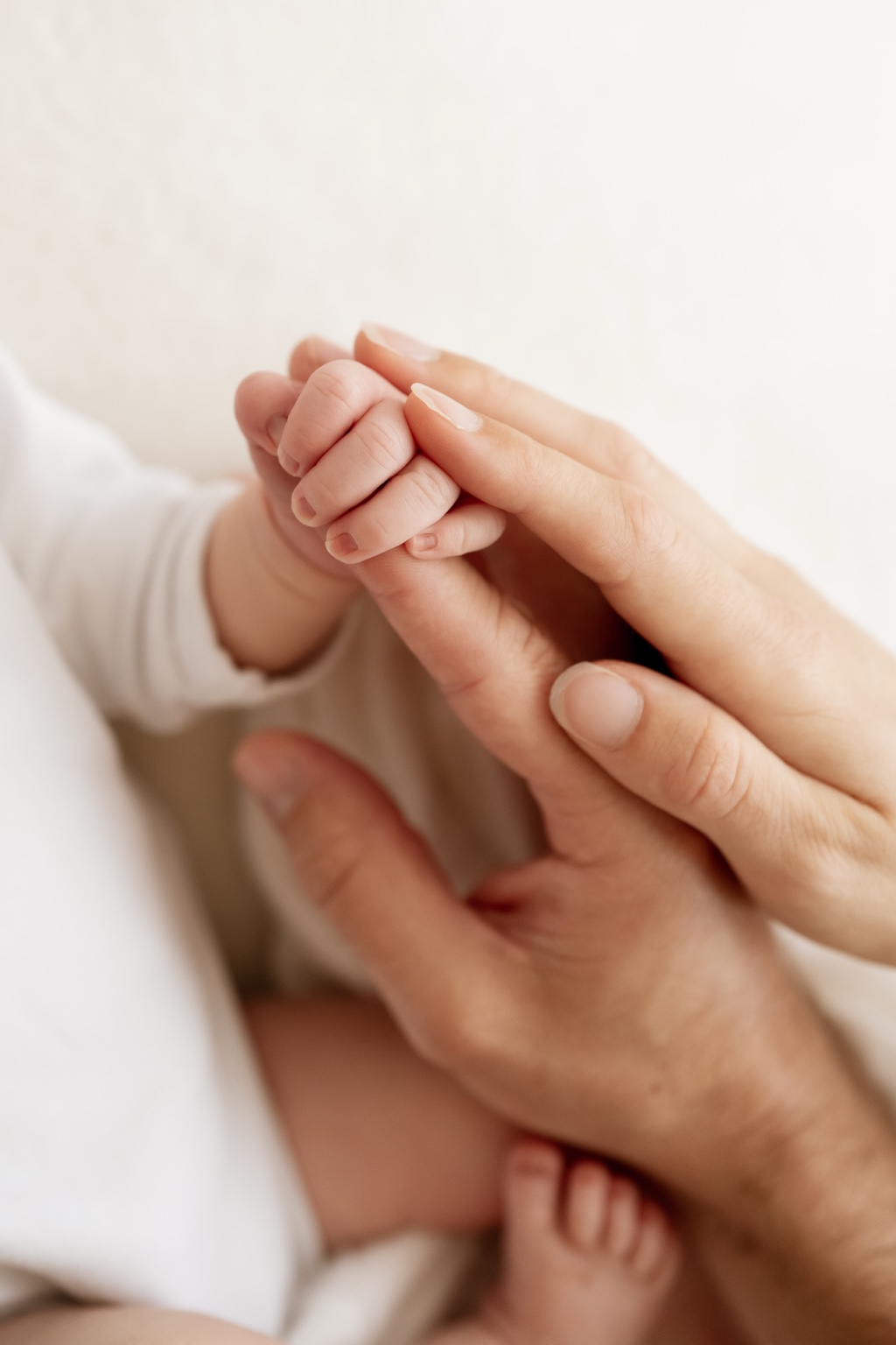 Zarte Babyhand zwischen den Händen der Eltern